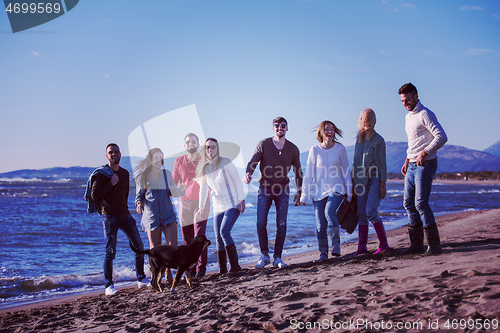 Image of young friends jumping together at autumn beach