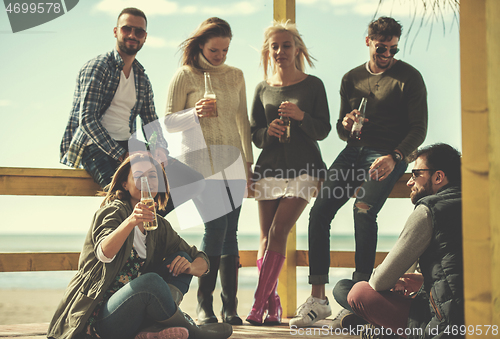 Image of Group of friends having fun on autumn day at beach