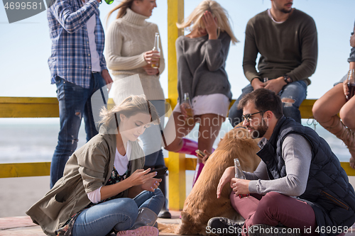 Image of Group of friends having fun on autumn day at beach