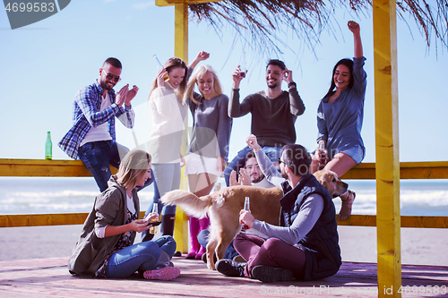 Image of Group of friends having fun on autumn day at beach