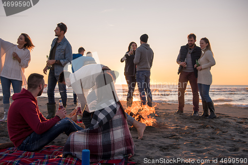 Image of Couple enjoying with friends at sunset on the beach