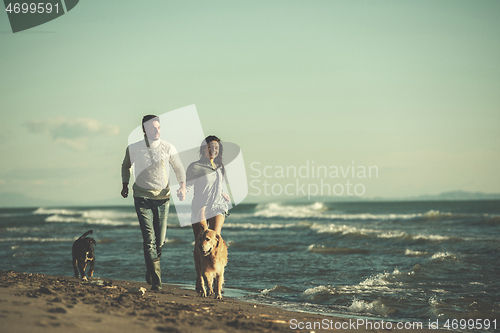 Image of couple with dog having fun on beach on autmun day