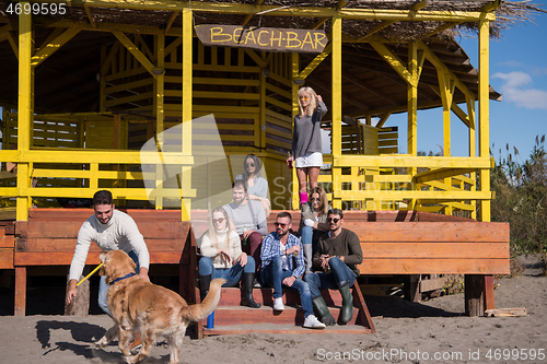 Image of Group of friends having fun on autumn day at beach