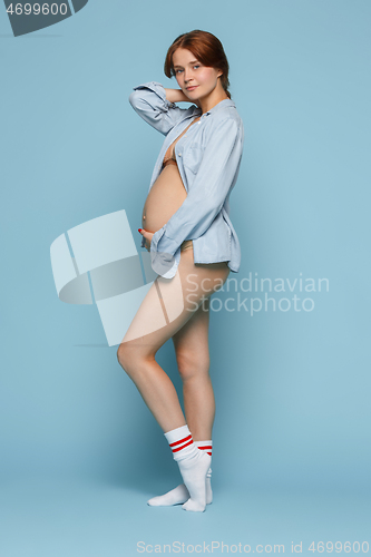 Image of Young beautiful pregnant woman posing on blue background