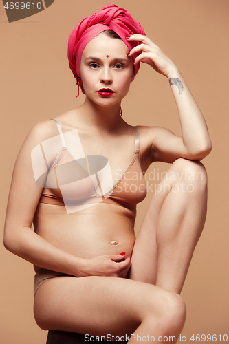 Image of Young beautiful pregnant woman posing on brown background