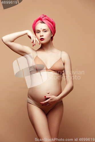 Image of Young beautiful pregnant woman posing on brown background