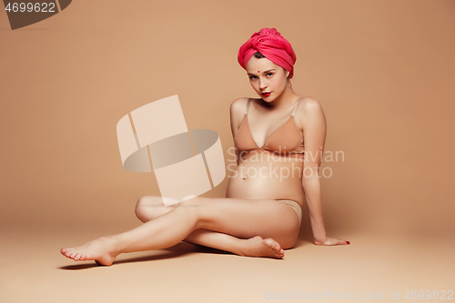 Image of Young beautiful pregnant woman posing on brown background