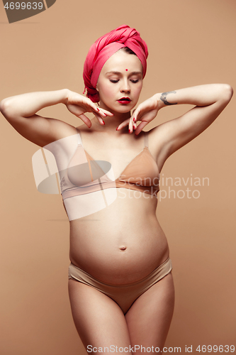 Image of Young beautiful pregnant woman posing on brown background
