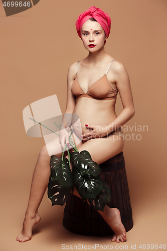 Image of Young beautiful pregnant woman posing on brown background