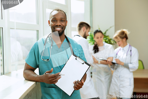 Image of Beautiful smiling african doctor over hospital background