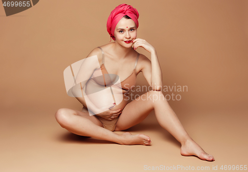 Image of Young beautiful pregnant woman posing on brown background