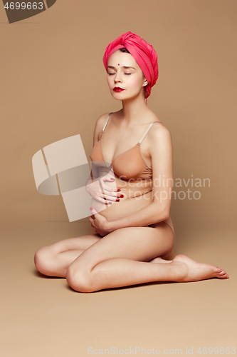 Image of Young beautiful pregnant woman posing on brown background