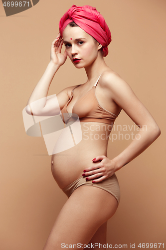 Image of Young beautiful pregnant woman posing on brown background