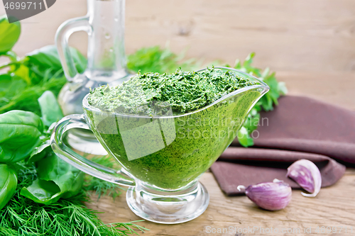 Image of Sauce of spicy greens in gravy boat on wooden board