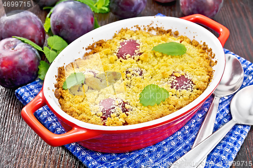 Image of Crumble with plum in brazier on dark board