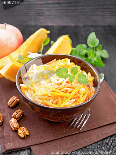 Image of Salad of pumpkin and apple with nuts in bowl on black board