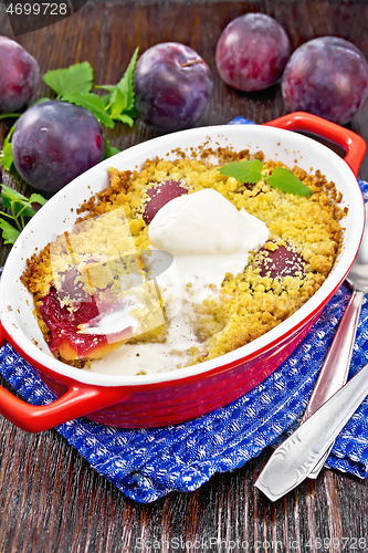 Image of Crumble with plum and ice cream in brazier on wooden board