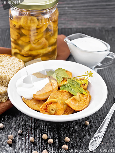 Image of Mushrooms salted with sour cream in plate on black wooden board