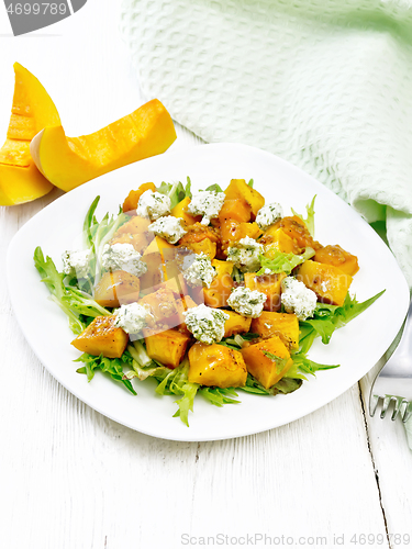 Image of Salad of pumpkin and cheese in plate on wooden board