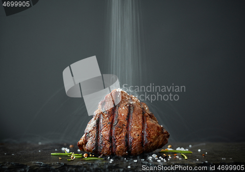 Image of the salt is poured onto freshly grilled steak