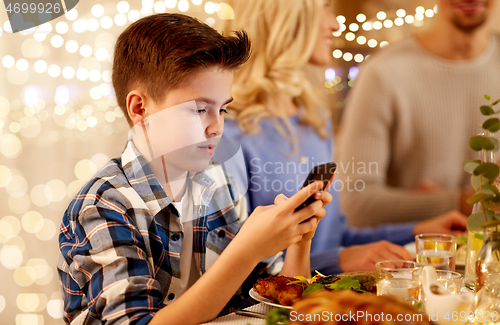 Image of boy with smartphone at family dinner party