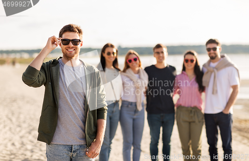 Image of man in sunglasses with friends on beach in summer