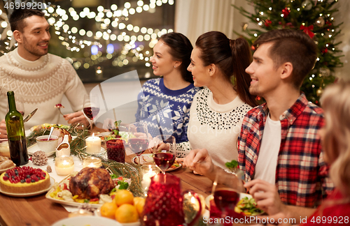 Image of happy friends having christmas dinner at home