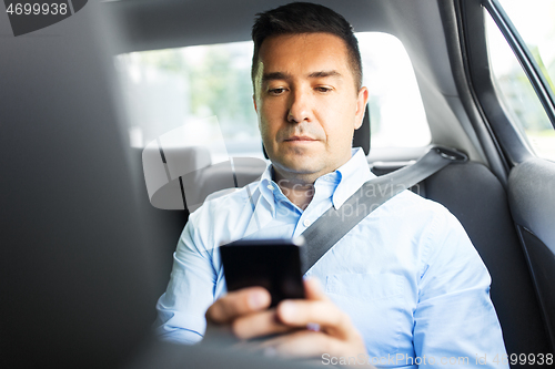 Image of passenger or businessman using smartphone in car