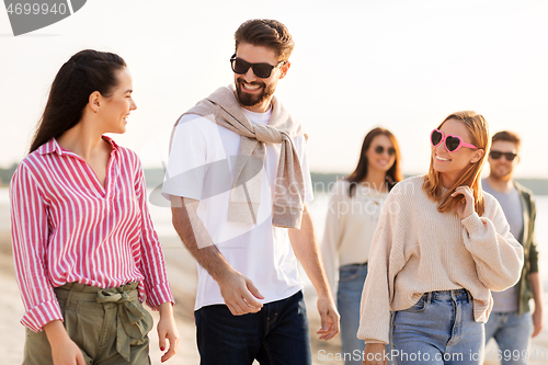 Image of happy friends walking along summer beach