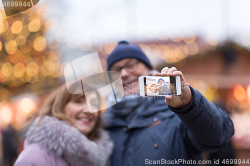 Image of senior couple taking selfie at christmas market