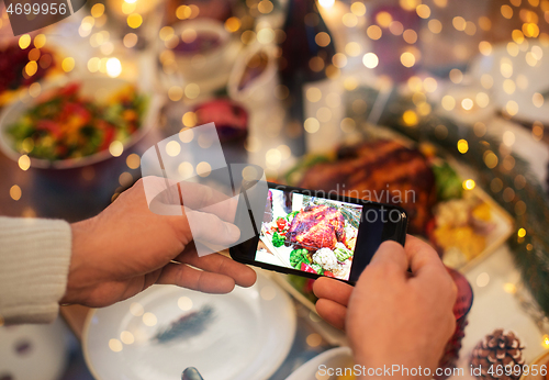 Image of hands photographing food at christmas dinner