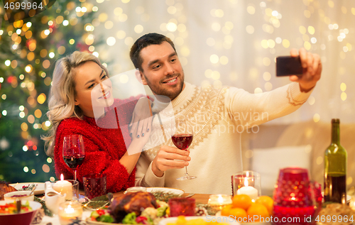 Image of happy couple taking selfie at christmas dinner