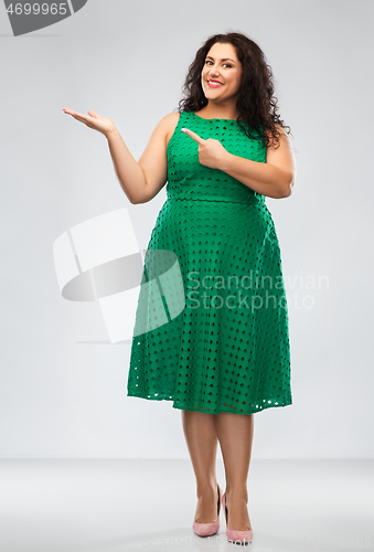 Image of happy woman in green pointing fingers at something