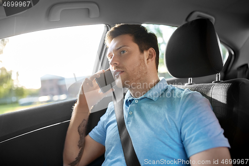 Image of male passenger calling on smartphone in taxi car