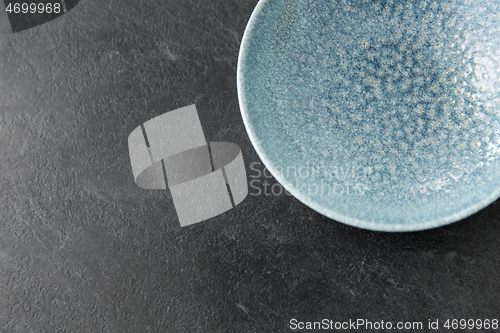 Image of close up of blue ceramic plate on slate background