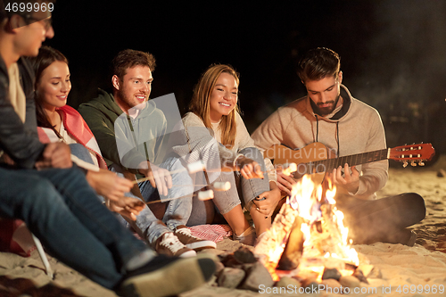 Image of friends roasting marshmallow and playing guitar