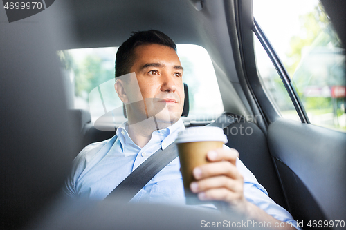 Image of businessman with takeaway coffee on car back seat