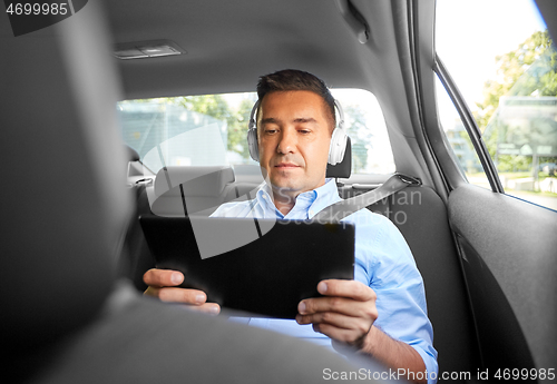 Image of passenger with headphones using tablet pc in car