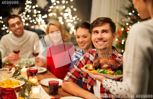 Image of happy friends having christmas dinner at home