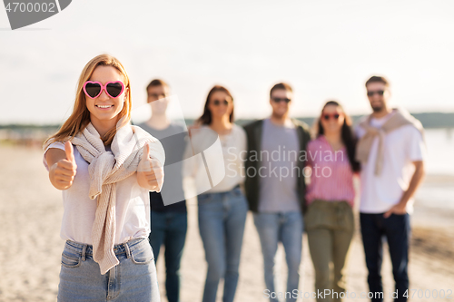 Image of woman with friends on beach showing thumbs up