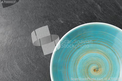 Image of close up of blue ceramic plate on slate background