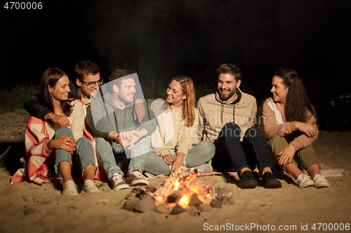 Image of group of friends sitting at camp fire on beach