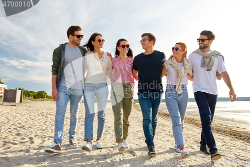 Image of happy friends walking along summer beach