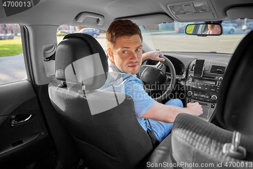 Image of man or driver driving car and looking back