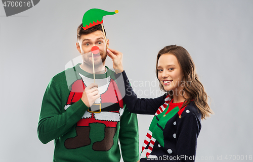 Image of couple with christmas party props in ugly sweaters