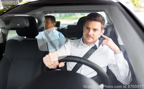 Image of male driver with wireless earphones driving car