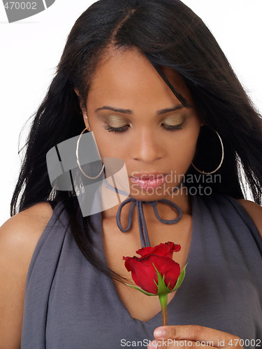 Image of Young black woman looking down at red rose