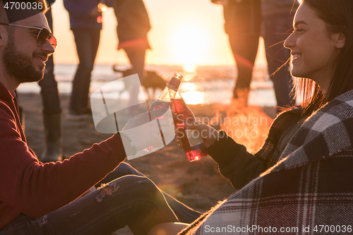 Image of Couple enjoying with friends at sunset on the beach