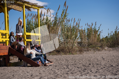 Image of Group of friends having fun on autumn day at beach