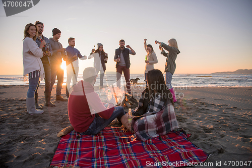 Image of Couple enjoying with friends at sunset on the beach